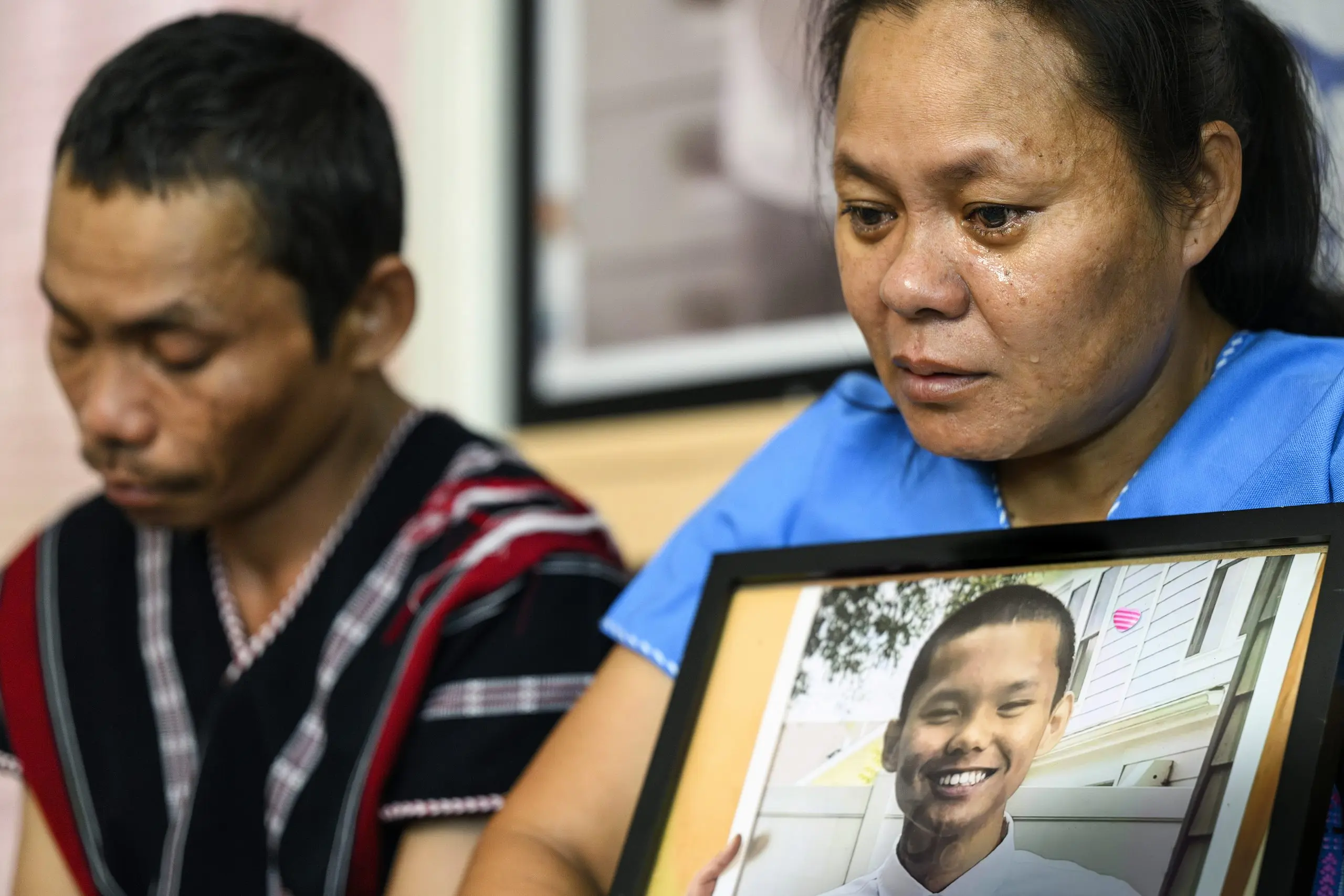 Photo of mother crying while holding a photo of her son